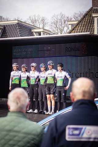 A group of cyclists on stage wearing Drentse 8 van Westerveld jerseys.