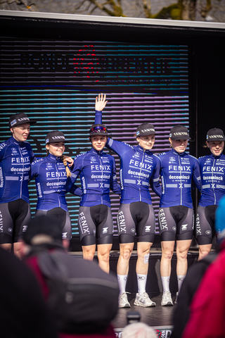 A group of professional cyclists posing for a photo with the Dutch word "fiets" on their uniforms.