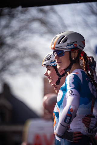 Three women wearing blue and white sports clothing are taking a photo together.