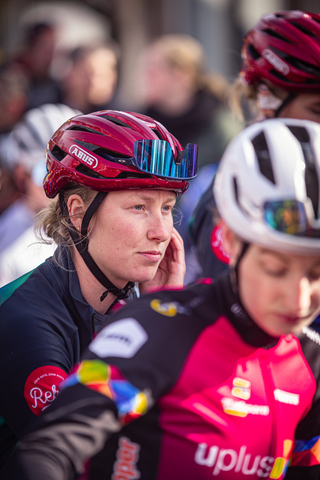 A woman wearing a red helmet is next to two other cyclists.