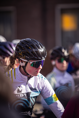 A young female cyclist wearing a helmet and glasses with a black bike.