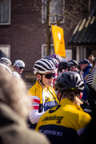 A cyclist in a yellow jersey is part of the Wielrennen group.