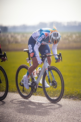 A person riding a bicycle down the road, dressed in a blue jersey with number 8 and the word "B" on it.