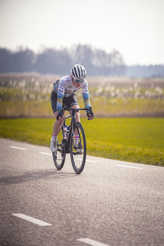 A cyclist wearing blue and white on a bike on the road.