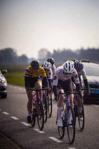 Eight cyclists on a road with the leader wearing a yellow jersey.