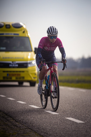 A woman in a pink jersey rides her bicycle on the road.