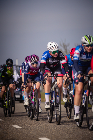 Six cyclists on a track with one of them wearing a blue jersey with the word "Bouwke" on it.