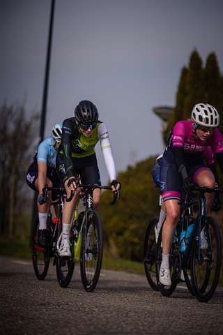 Three cyclists on a street with one wearing a helmet and another wearing sunglasses.