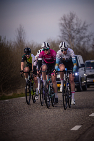 A group of cyclists race down a road in the Netherlands.