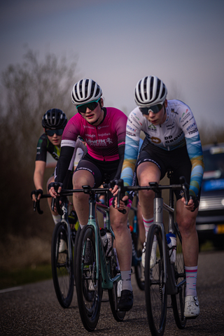 Three cyclists are racing in a group on a course with the number 8 visible on the road.