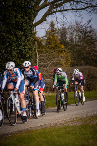 Eight cyclists are wearing helmets as they ride along a trail.