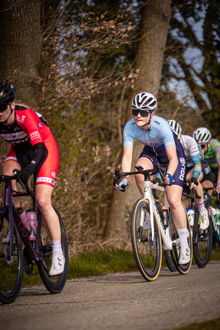 A group of cyclists race down a path on a sunny day.