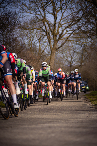 A group of cyclists wearing helmets are riding down a road.