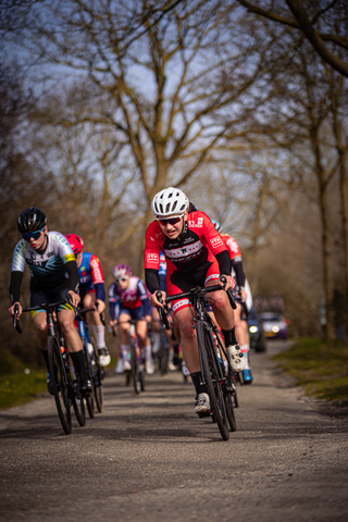 A group of cyclists are racing down a road during the Drentse 8 Van Westerveld race.