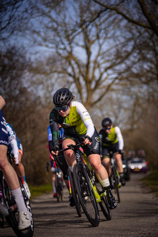 a group of cyclists race on a road with one in the foreground.