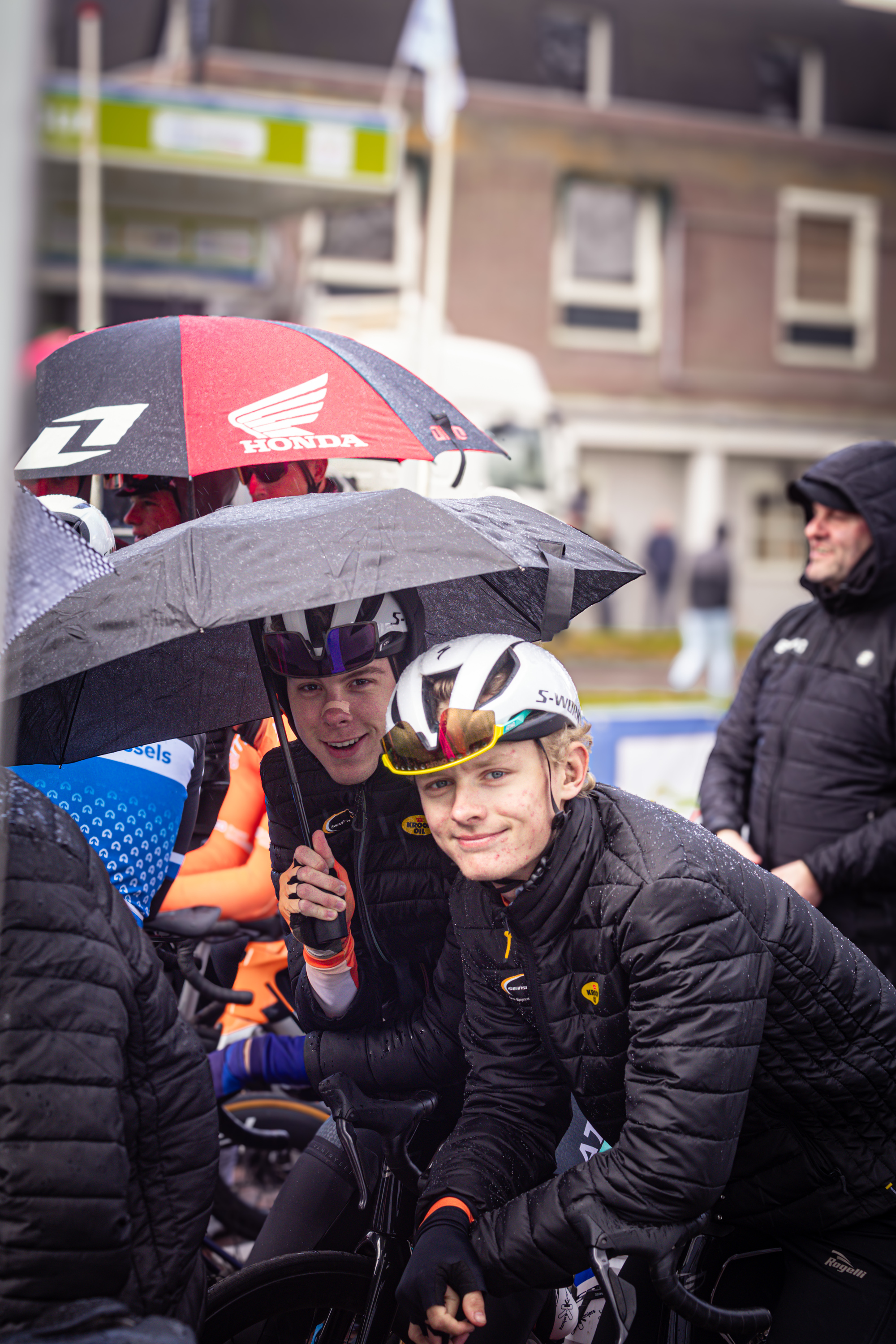 A group of cyclists with helmets and black jackets, one with a smile on his face.