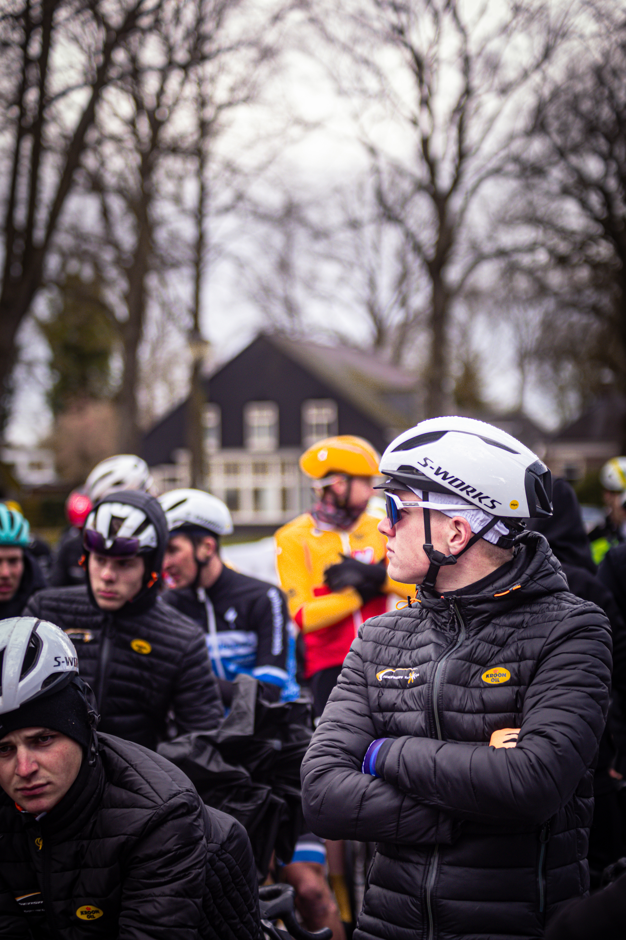 A group of cyclists are preparing for a race, one of them is wearing a black jacket with the number 17 on it.