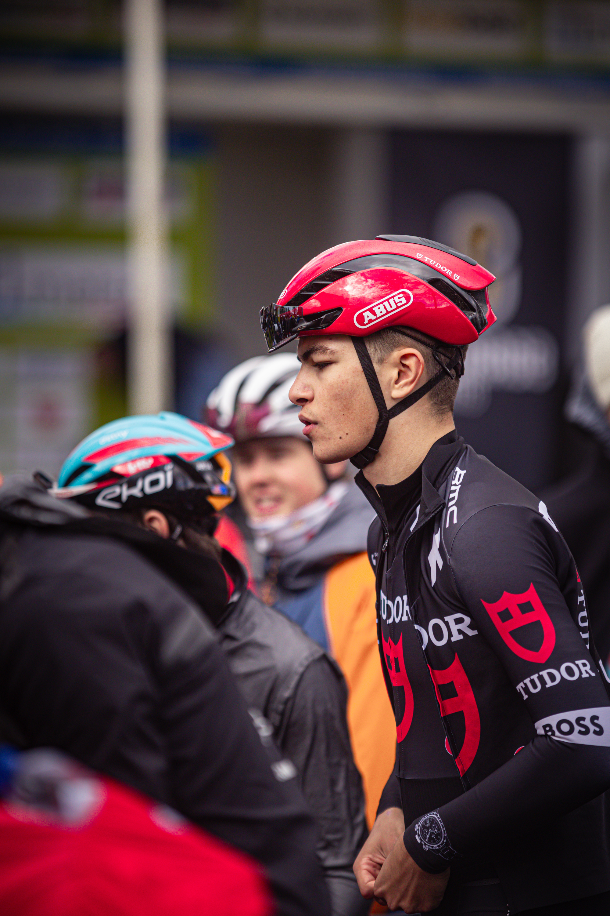 A person in a black shirt and red helmet looks away with their chin held high.