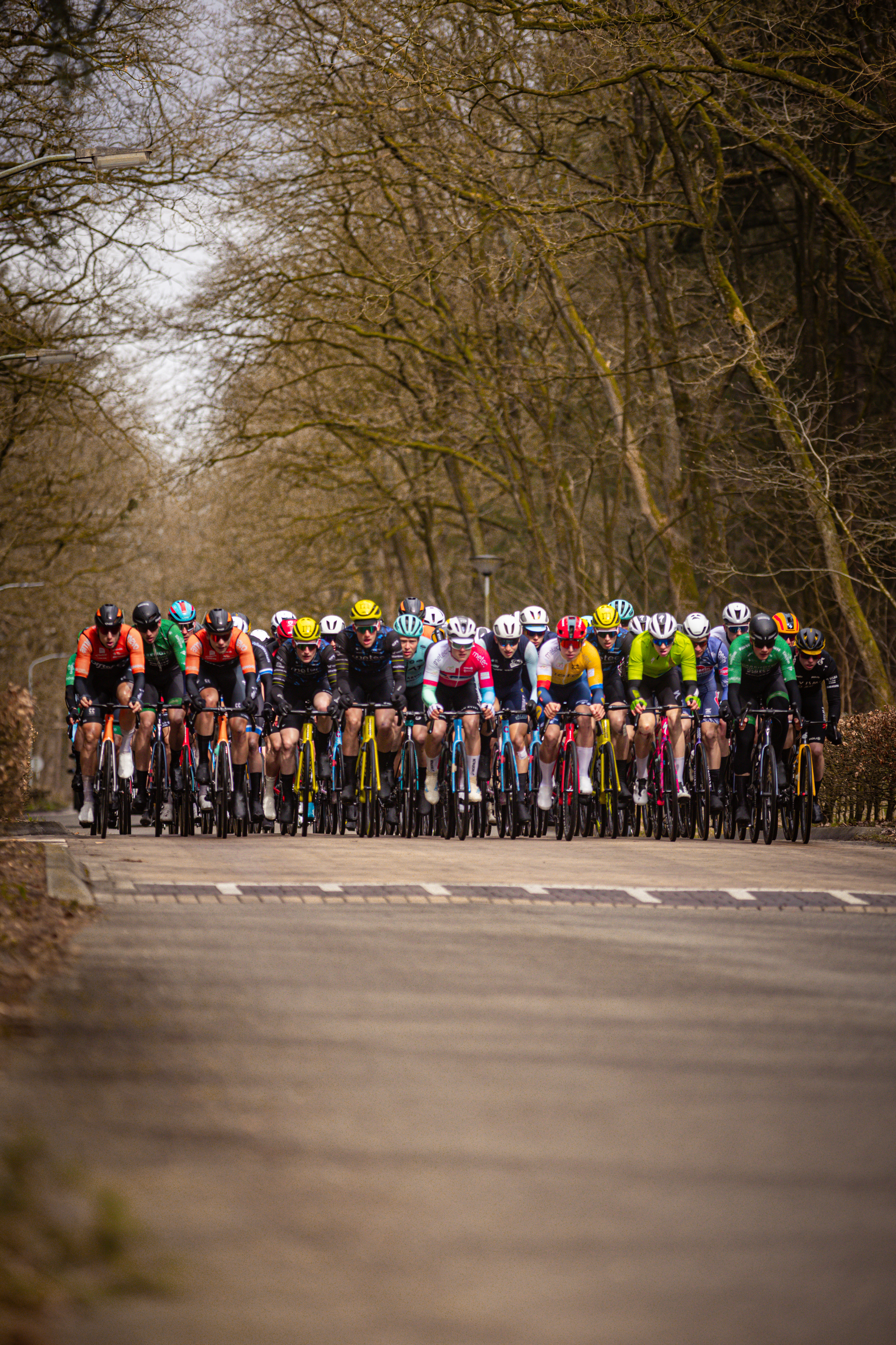 A group of bicycle racers, all wearing helmets and riding bikes.