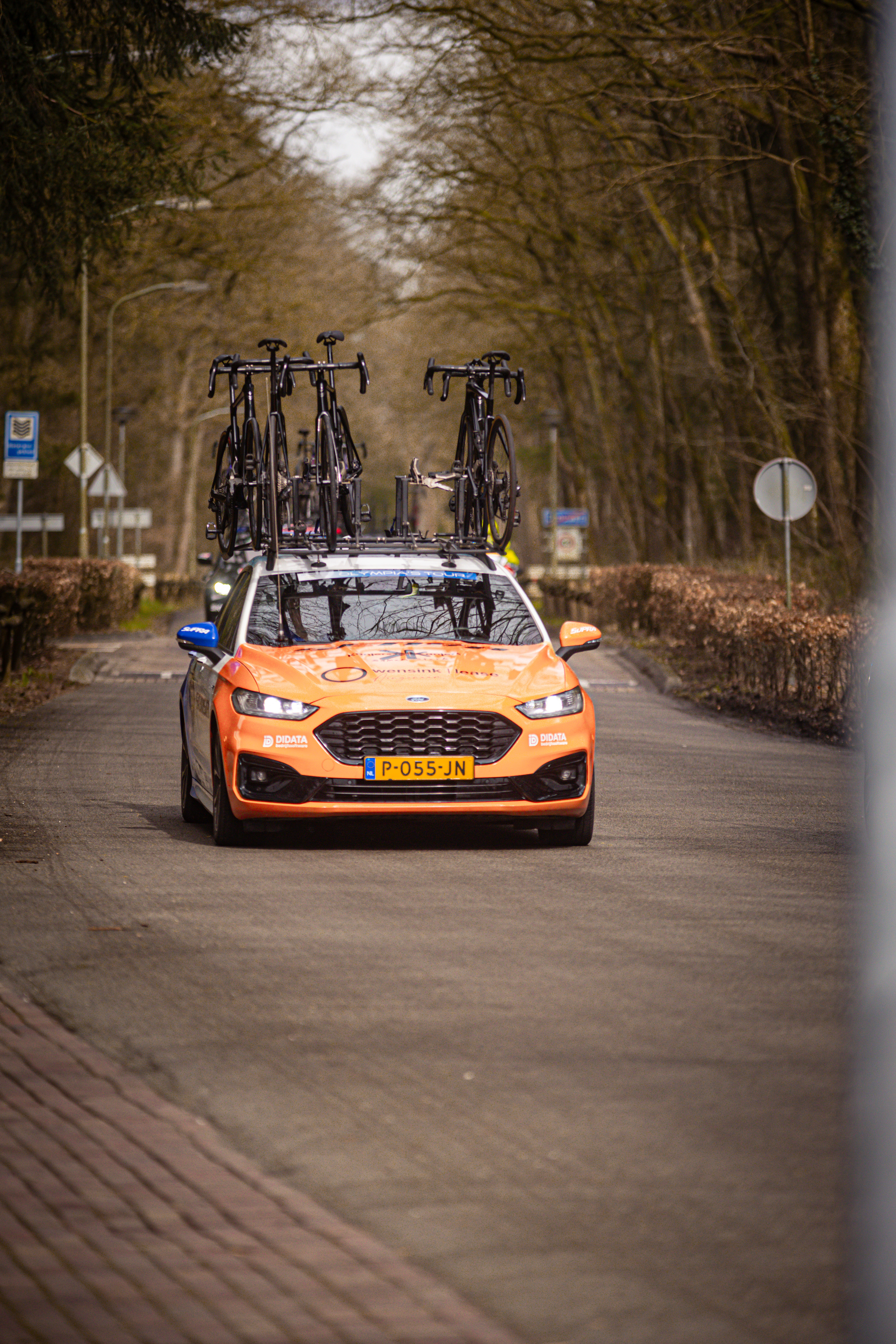 A group of bicycles on the back of a red car. The license plate is yellow and says "K0D".