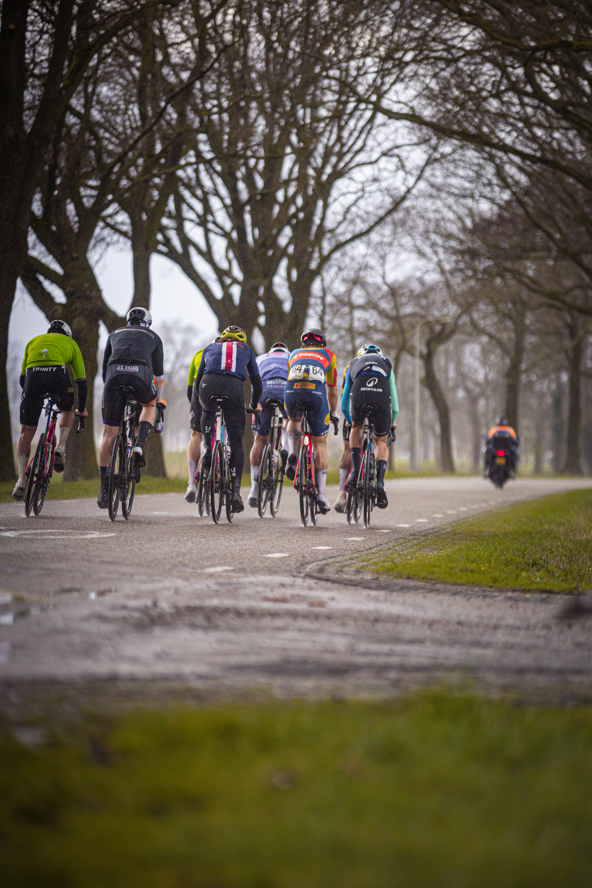 Group of cyclists are riding their bikes down a road.