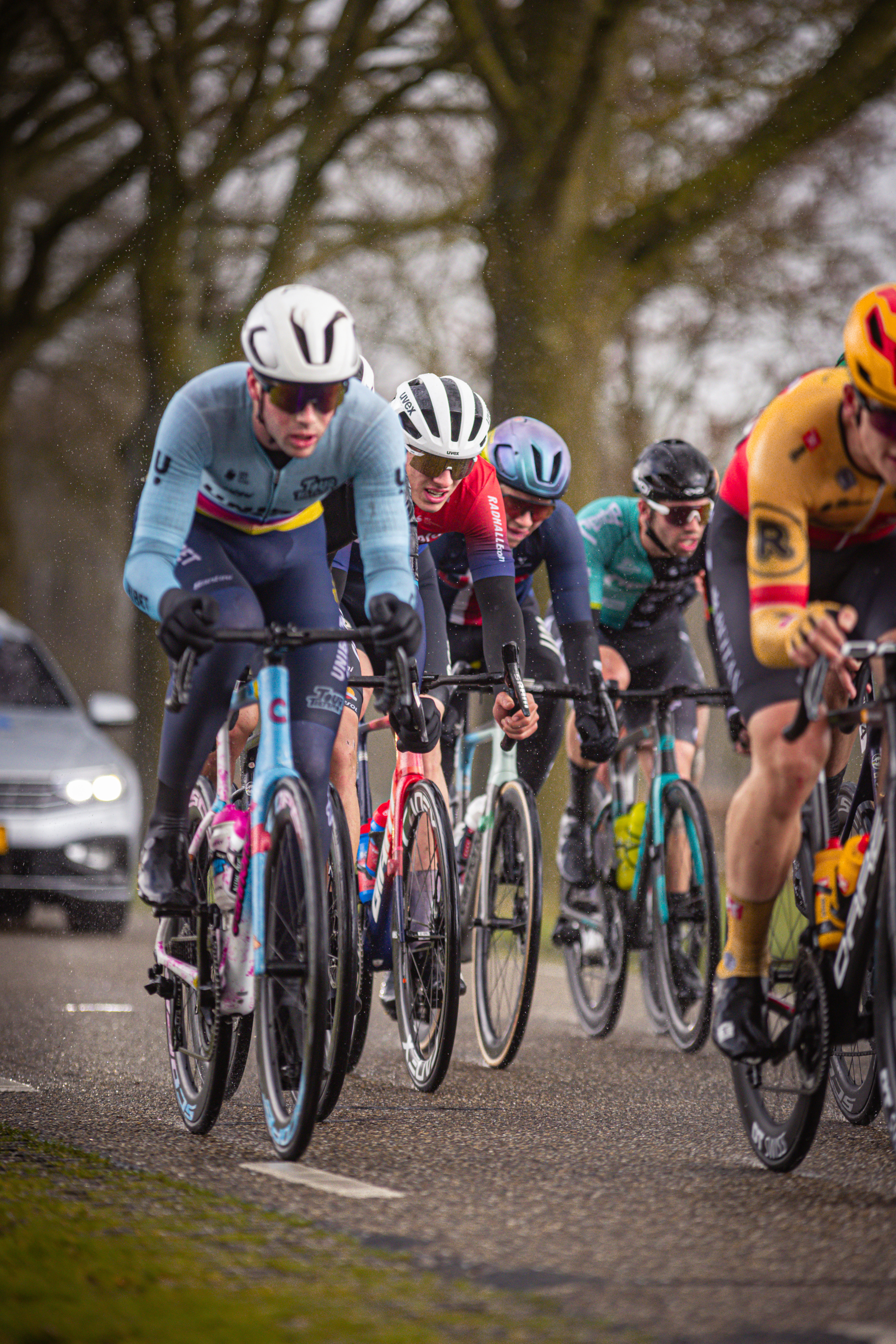 Four cyclists in racing gear are riding closely together on a road.