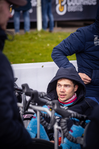 A boy sitting in a group of bicycles with his head down.