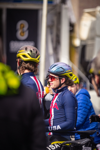 A cyclist with the word USA on their chest jersey is wearing a blue and white bike helmet.