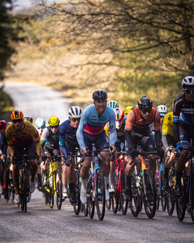 A group of cyclists are racing down a street in a competition.