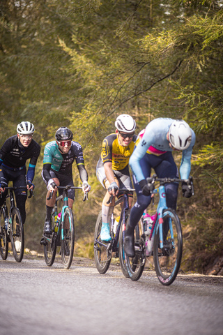 A group of cyclists are racing in a race around the corner.