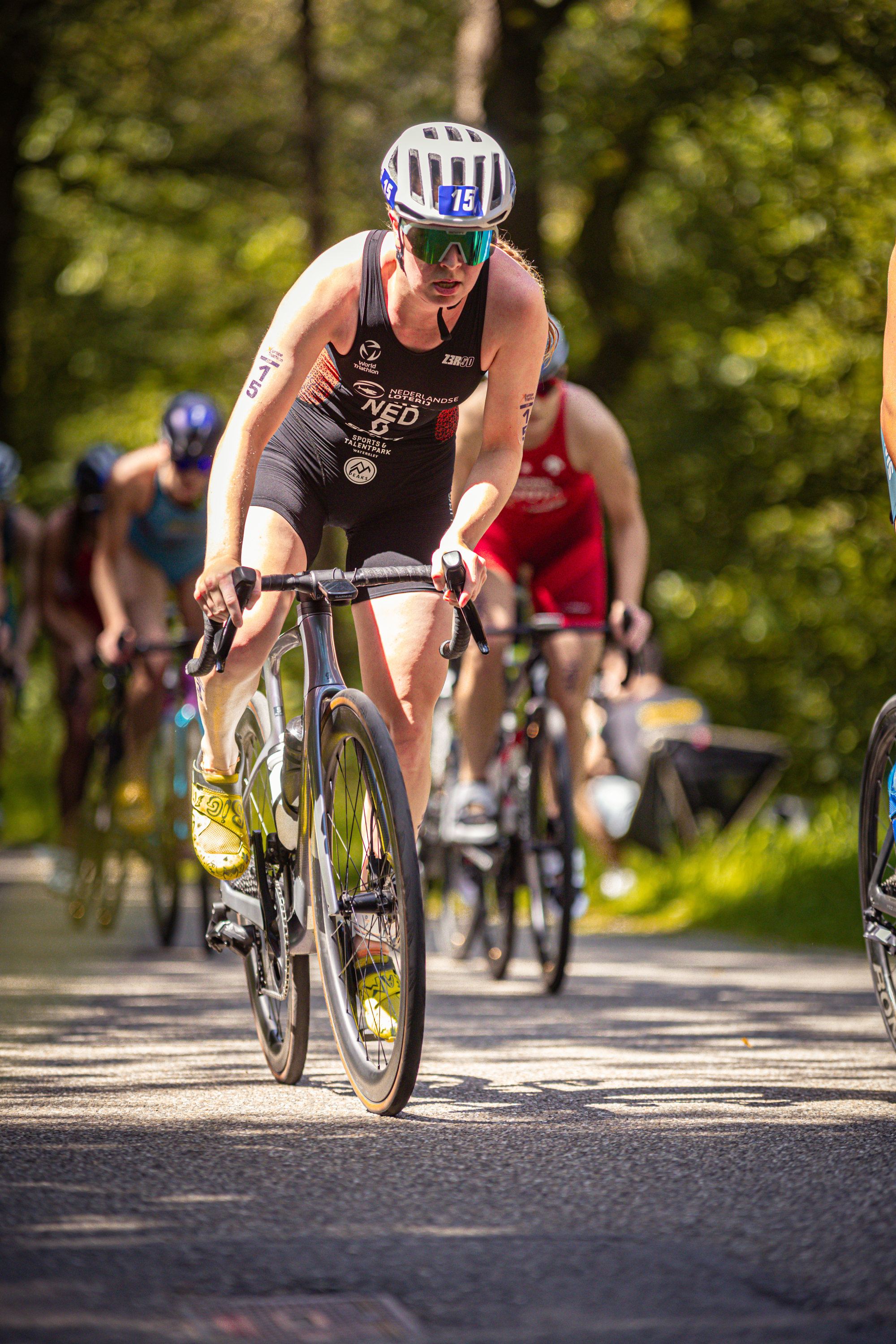 A woman wearing a black tank top and the letters ETU on her back is riding a bike.