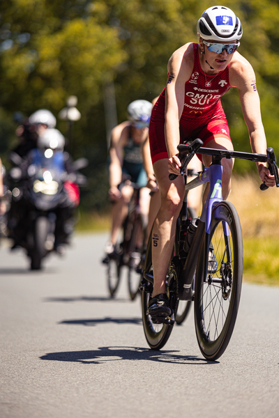 A cyclist is riding in a triathlon race sponsored by Elite Dames.