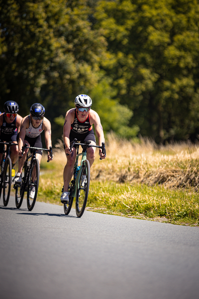 Two cyclists are riding through a grassy field as they participate in the Elite Triathlon Union race.