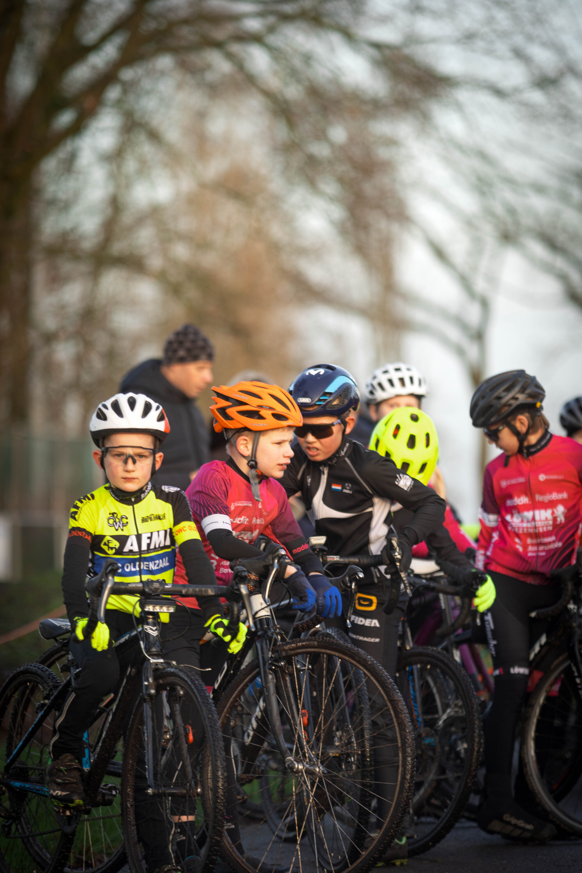 A group of young cyclists wearing helmets are preparing to compete in a race.