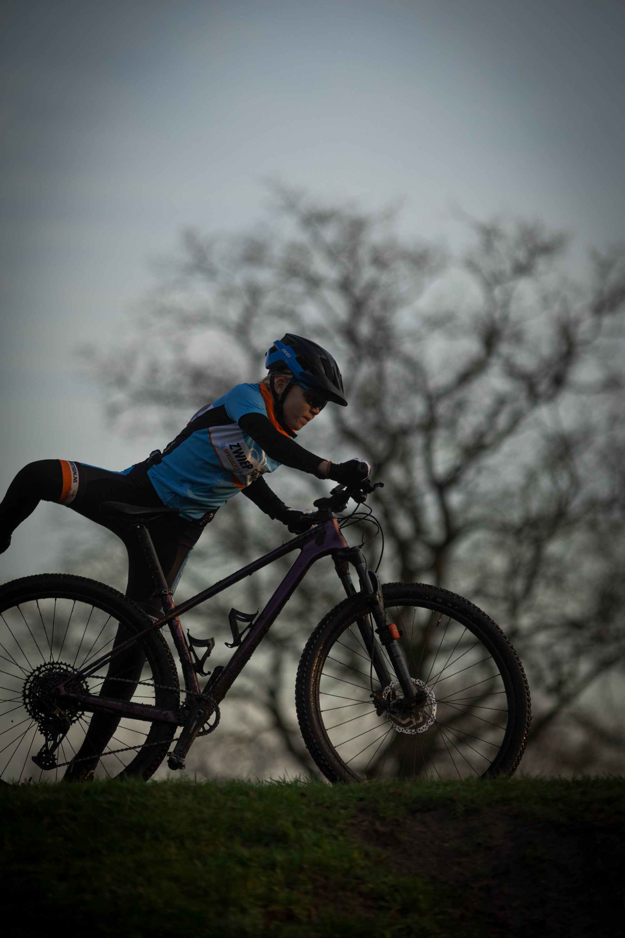 a young child is riding a purple bike with blue handle bars.