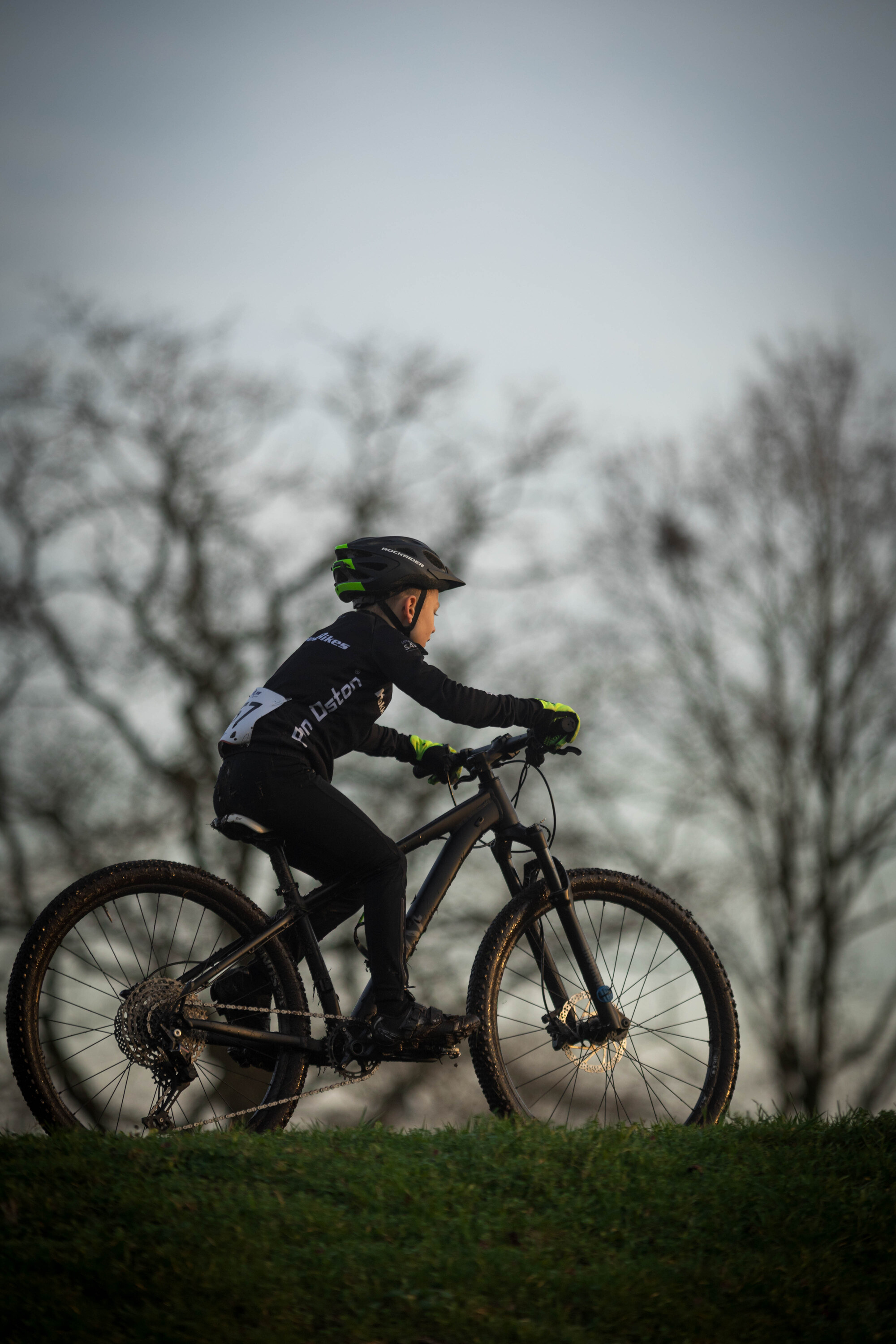 A child wearing a helmet is riding a black and white bike.