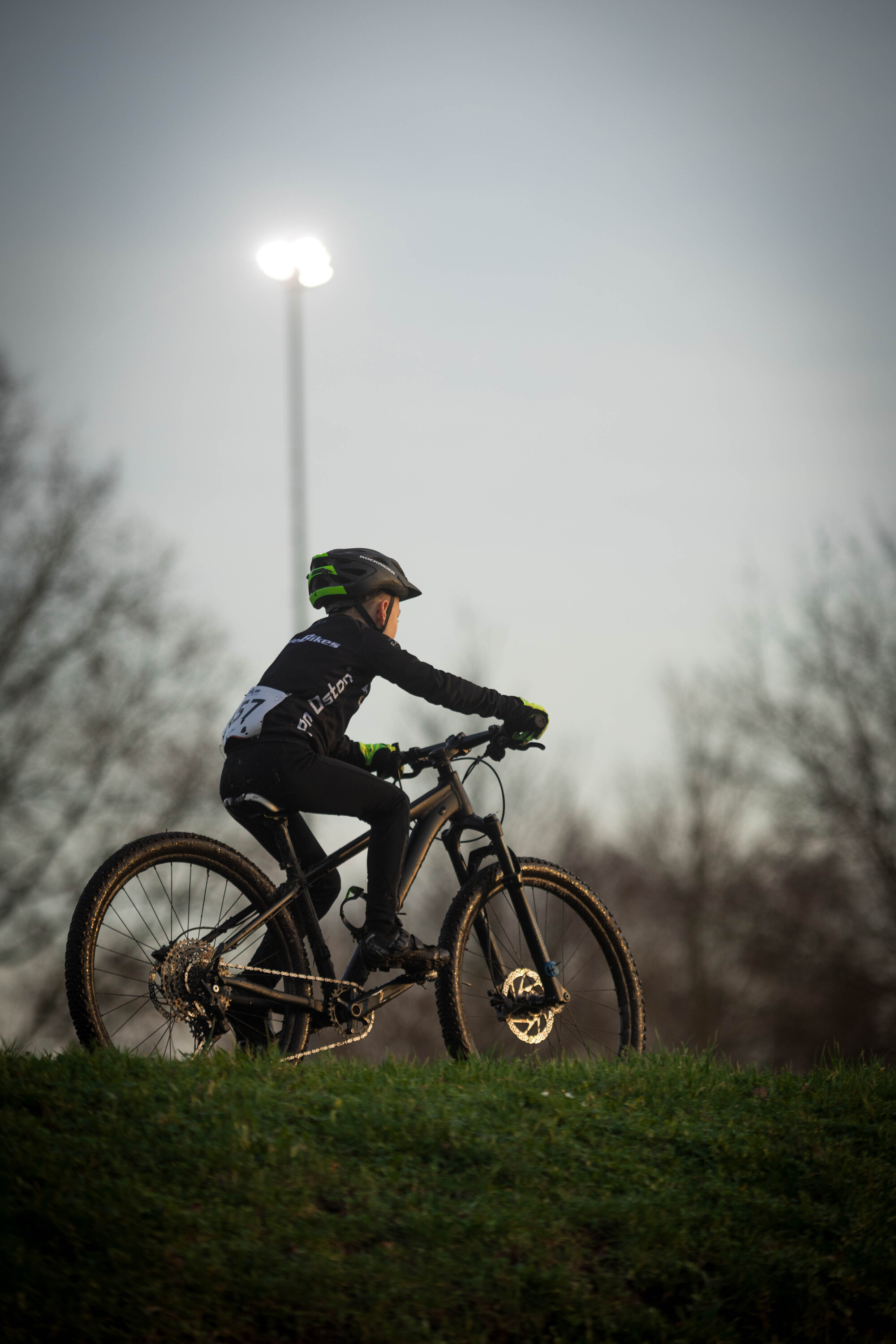 A person on a bike with a helmet on in front of a light.