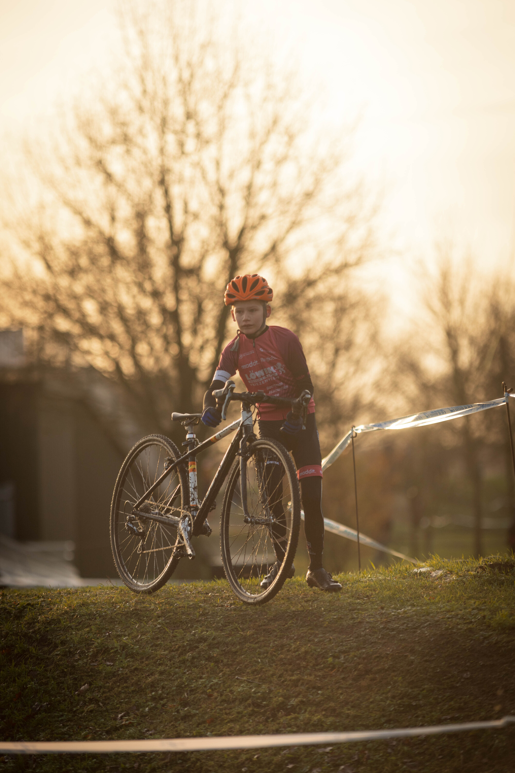 A young child is riding a bicycle at a cyclocross event.