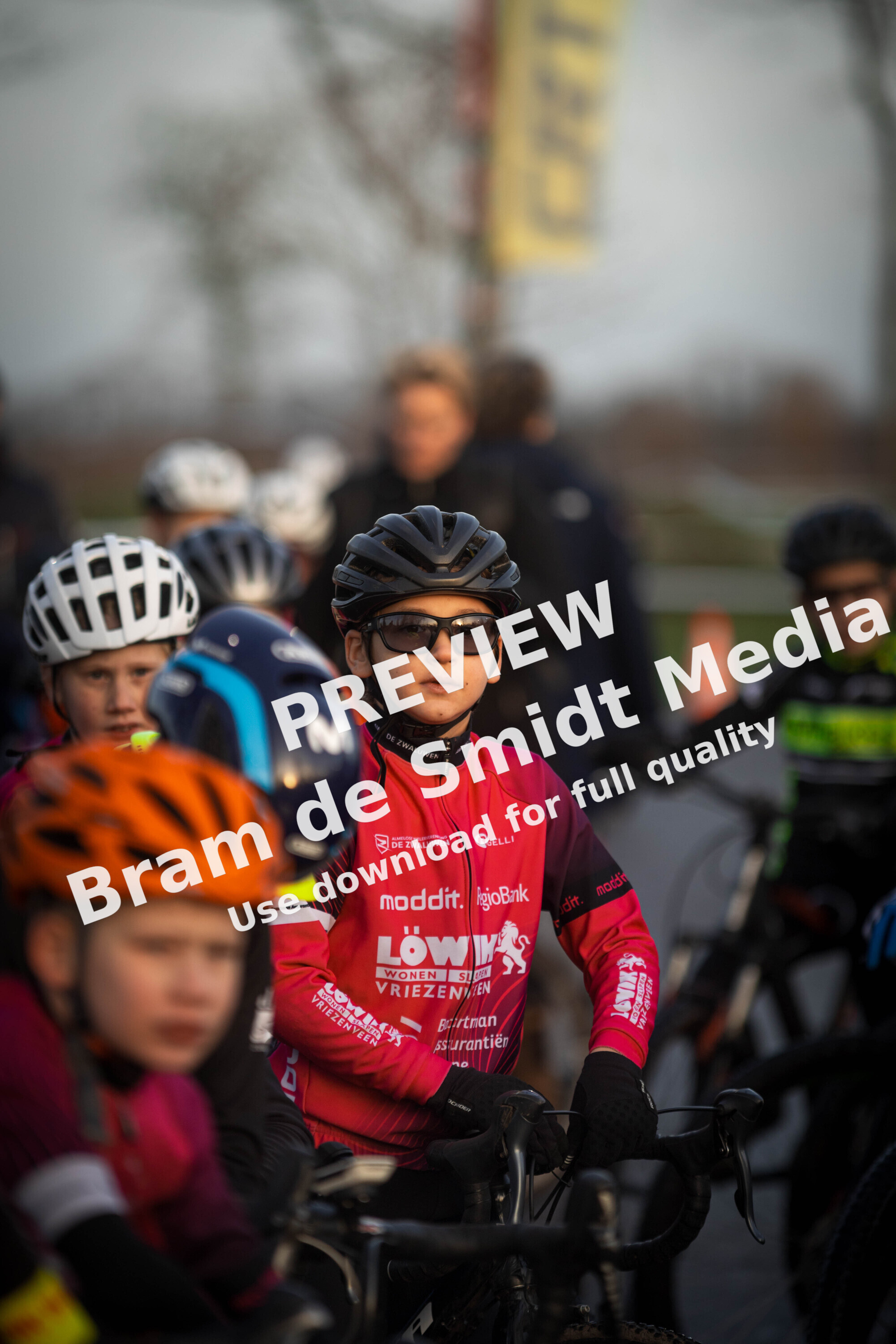 A group of young cyclists wearing colorful jerseys for a Jeug cyclocross event sponsored by GOW.