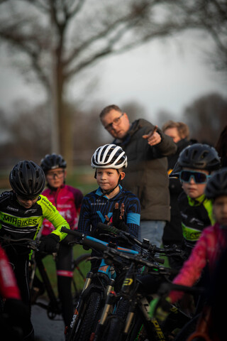 A group of young children wearing helmets are playing a game of bicycle racing.