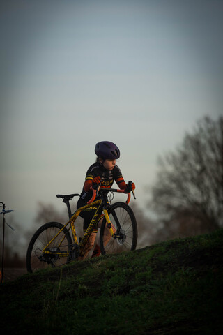 A child in a purple helmet is riding a yellow and black bike.