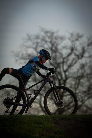 a young child is riding a purple bike with blue handle bars.