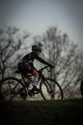 A person wearing a blue helmet riding a black bike with the letter G on the back.