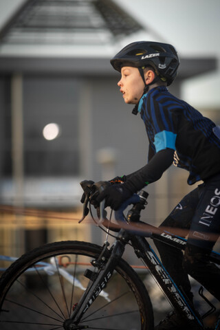 A person in a black and blue jacket riding a bike.