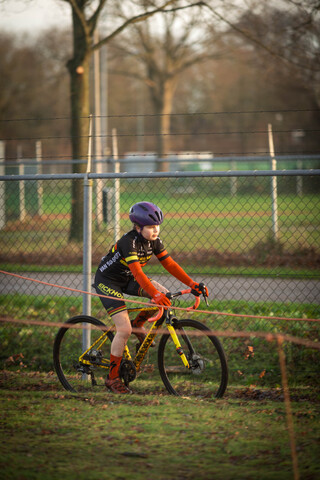 A young girl on a yellow bike wearing a black and red shirt.