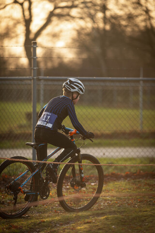 A man wearing a blue helmet on the back of his bike is wearing a number 2.