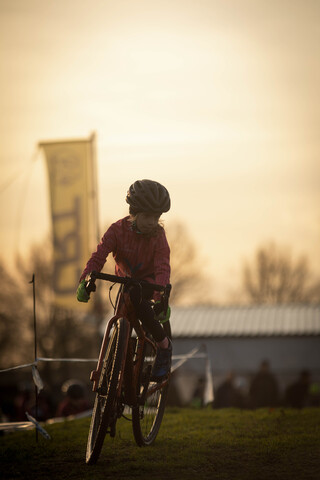 Jeugd 1+2 cyclocross competition on a sunny day with grass field and spectators in the background.