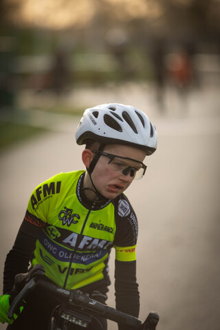 A young boy wearing a helmet and yellow cycling shirt is participating in the cyclocross event.