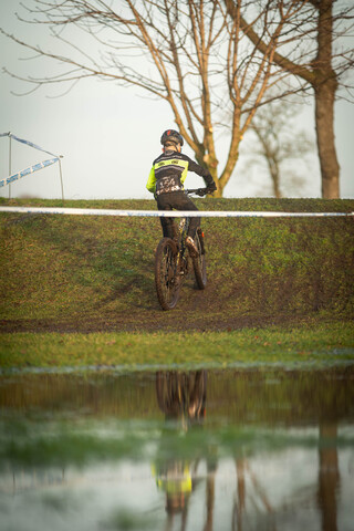 A person is riding a bike in the rain and has on a bright yellow shirt.