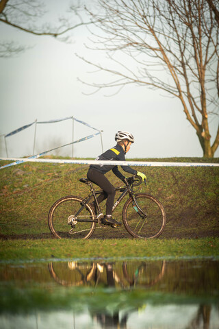 A man on a bicycle with a helmet is wearing a black and yellow cycling jersey.